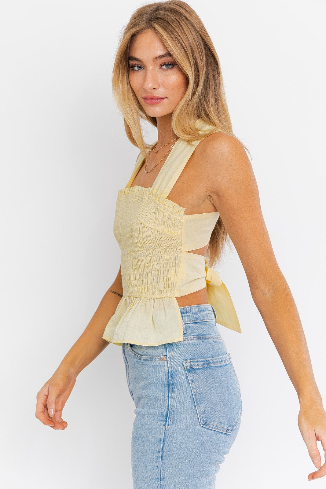 Introducing the Emma Smocked Peplum Top with a criss-cross back tie, a charming and fashionable addition to your wardrobe. This top features a sleeveless design that's perfect for warm days and a flattering peplum silhouette that adds a touch of flair. The smocked detailing enhances your figure and creates a comfortable fit, while the criss-cross back tie adds a playful and stylish accent, allowing for a customized fit.