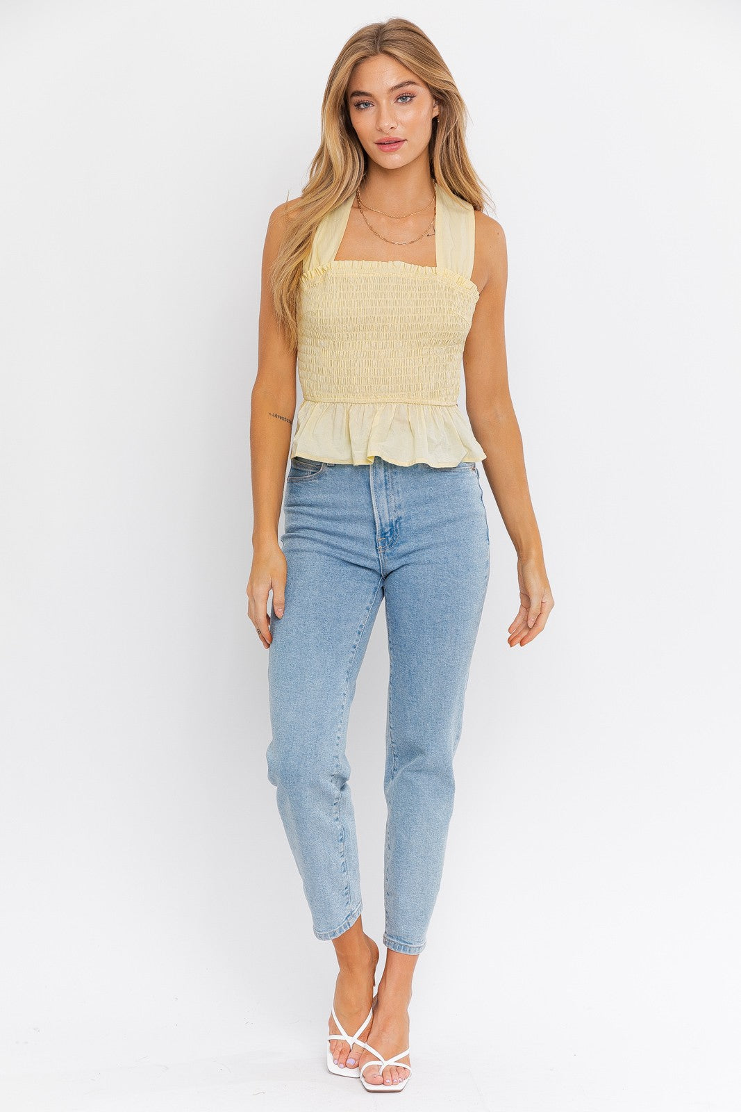 Introducing the Emma Smocked Peplum Top with a criss-cross back tie, a charming and fashionable addition to your wardrobe. This top features a sleeveless design that's perfect for warm days and a flattering peplum silhouette that adds a touch of flair. The smocked detailing enhances your figure and creates a comfortable fit, while the criss-cross back tie adds a playful and stylish accent, allowing for a customized fit.