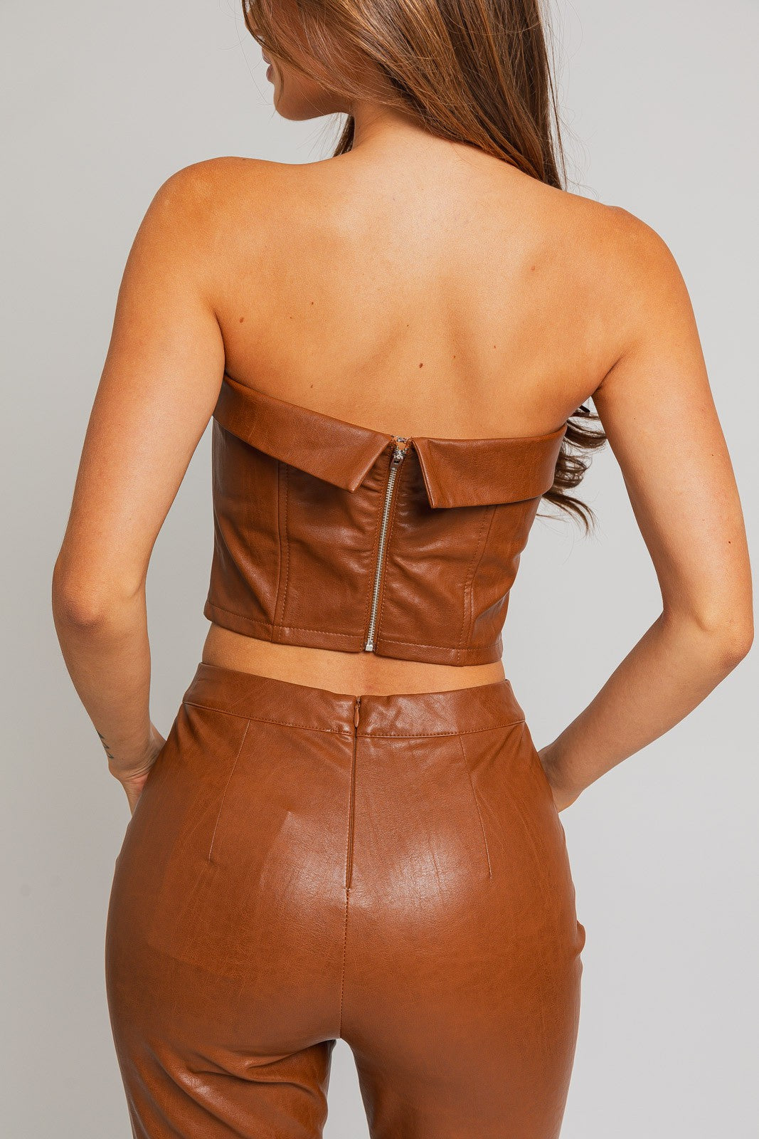 Revamp your wardrobe with our Emelie Faux Leather Corset Tube Top, a daring and chic addition to your collection. This trendy piece seamlessly combines the classic allure of a tube top with the edgy sophistication of a corset. The structured design enhances your silhouette, providing a flattering and on-trend look.