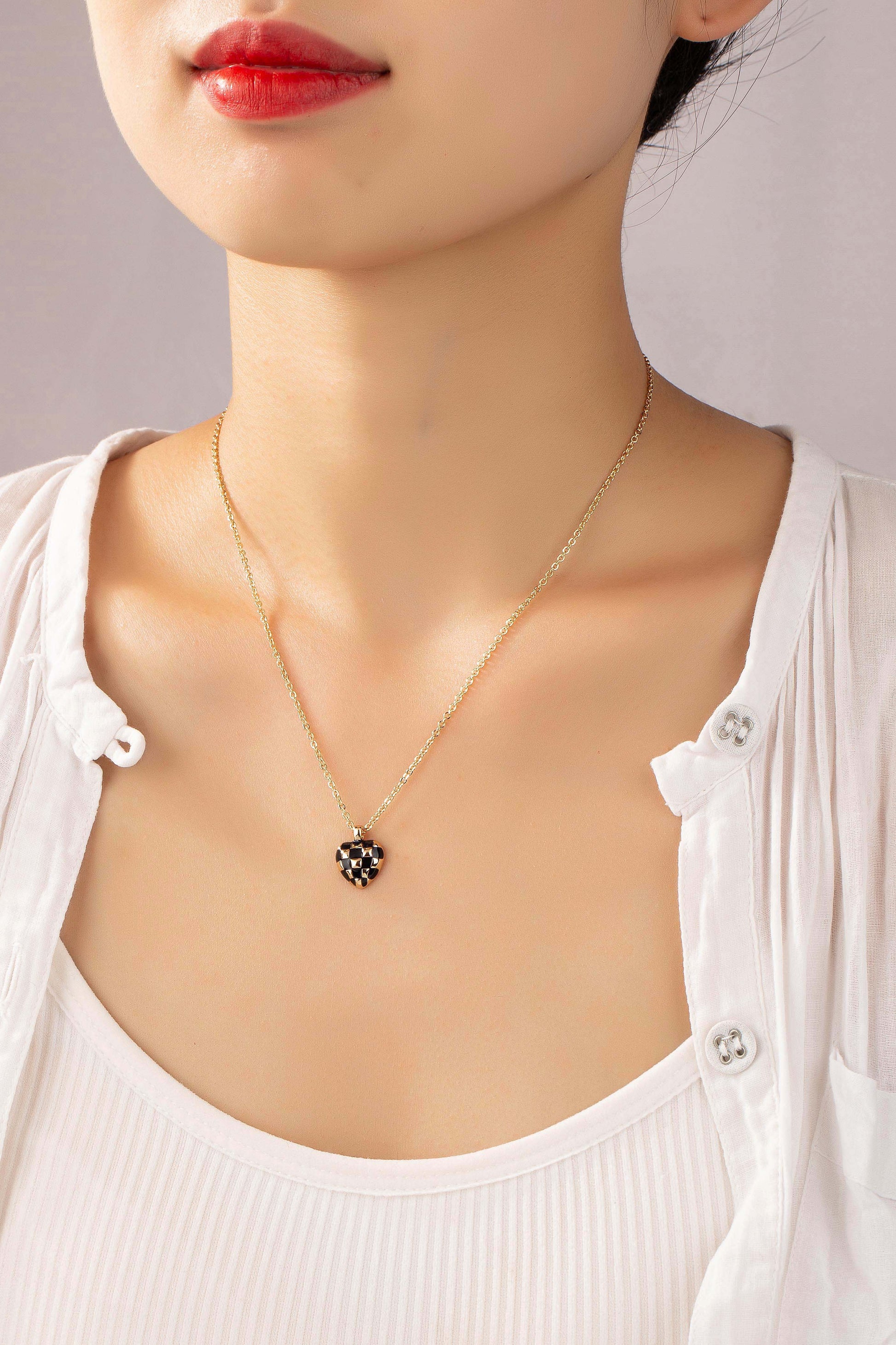 Adorn yourself with charm and style with our Checker Heart Pendant Necklace. This exquisite piece features a heart-shaped pendant crafted from alloy with enamel color, showcasing a playful checker pattern.