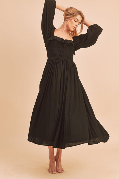 The Geri Dress boasts an eternally flattering shape, featuring a charmingly tied ruffled neckline, a smocked bodice, a lined skirt, and voluminous sleeves.