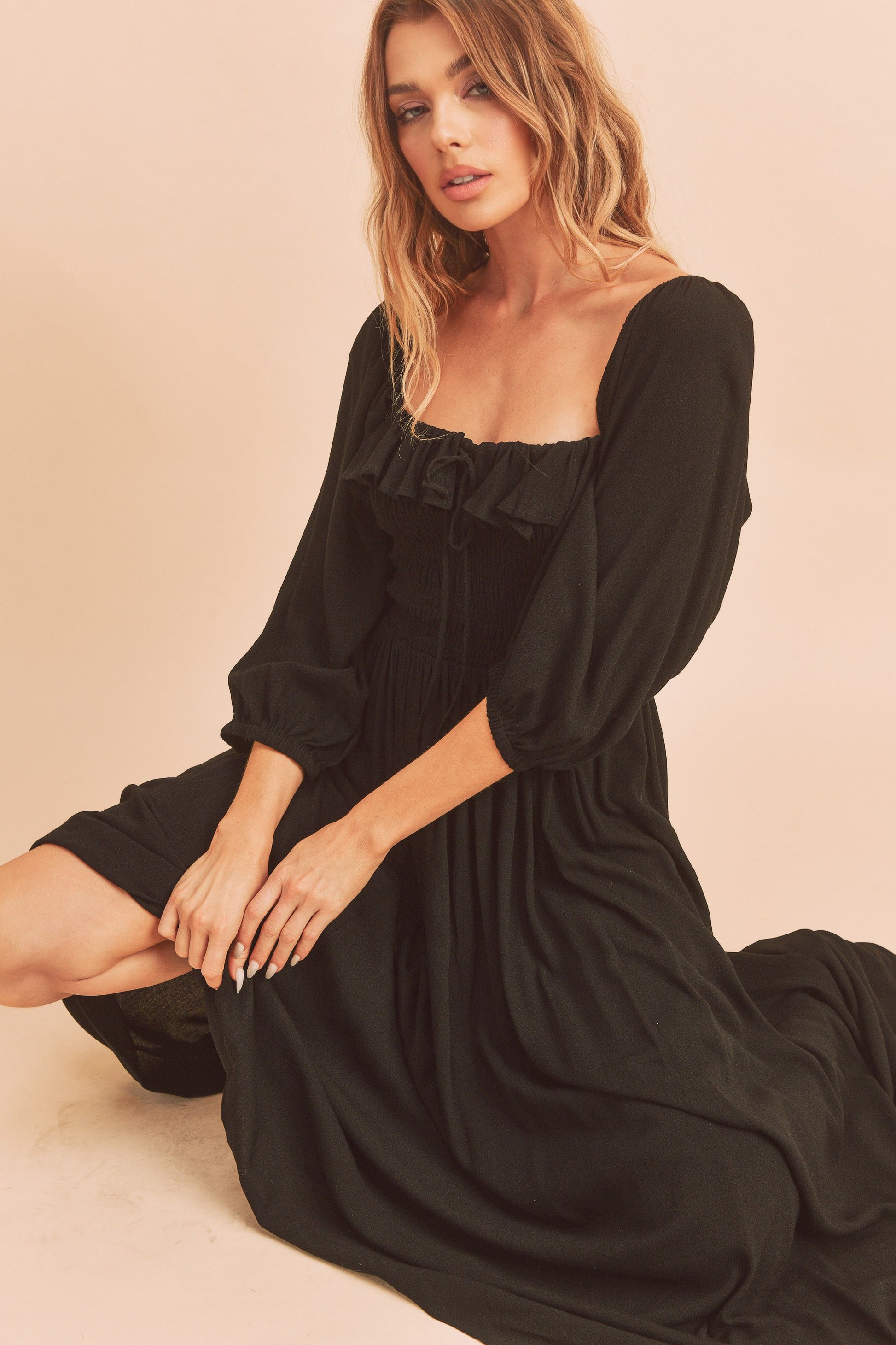 The Geri Dress boasts an eternally flattering shape, featuring a charmingly tied ruffled neckline, a smocked bodice, a lined skirt, and voluminous sleeves.