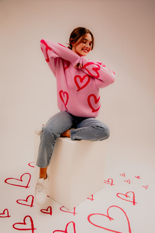 Embrace warmth and whimsy with our Long Sleeve Round Neck Heart Printed Sweater. This charming knit features an adorable heart pattern, adding a playful and romantic touch to your winter wardrobe.