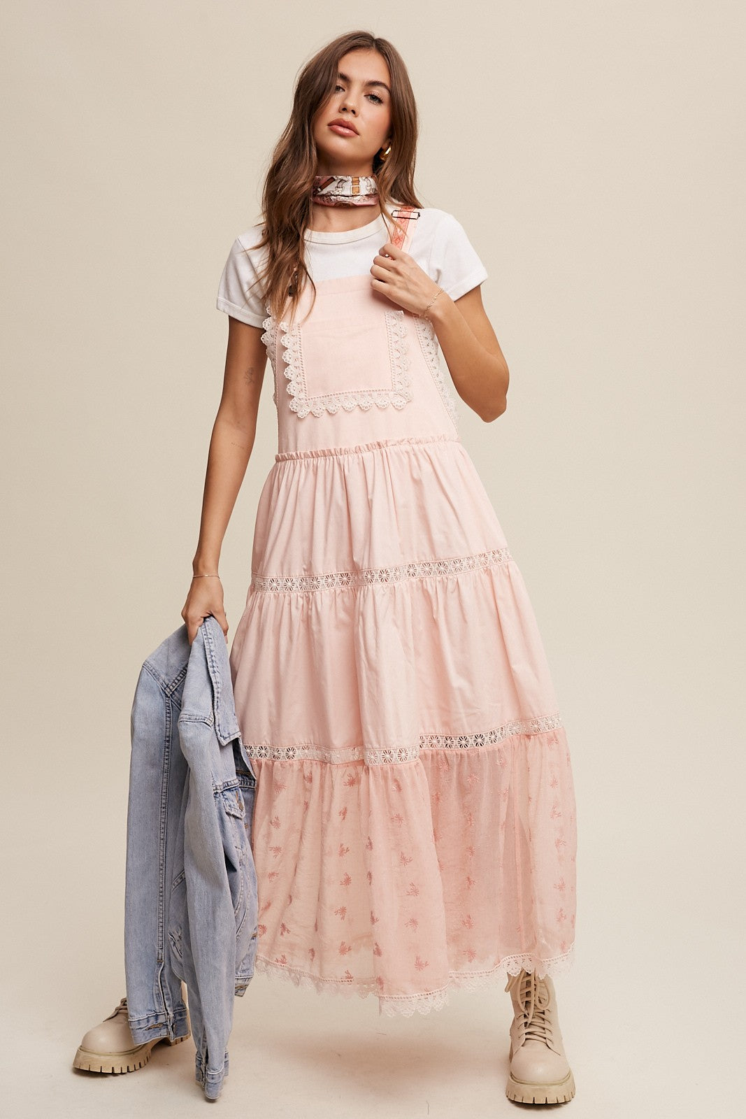 Step into summer romance with our Brooklynn Laced and Tiered Romantic Overall Maxi Dress. It features adjustable straps, a delicate kangaroo pocket, and embroidered crochet lace on the tiered skirt for a whimsical touch.