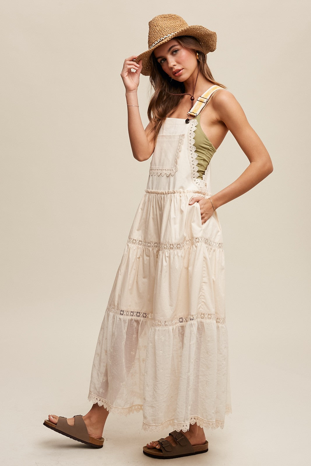 Step into summer romance with our Brooklynn Laced and Tiered Romantic Overall Maxi Dress. It features adjustable straps, a delicate kangaroo pocket, and embroidered crochet lace on the tiered skirt for a whimsical touch.