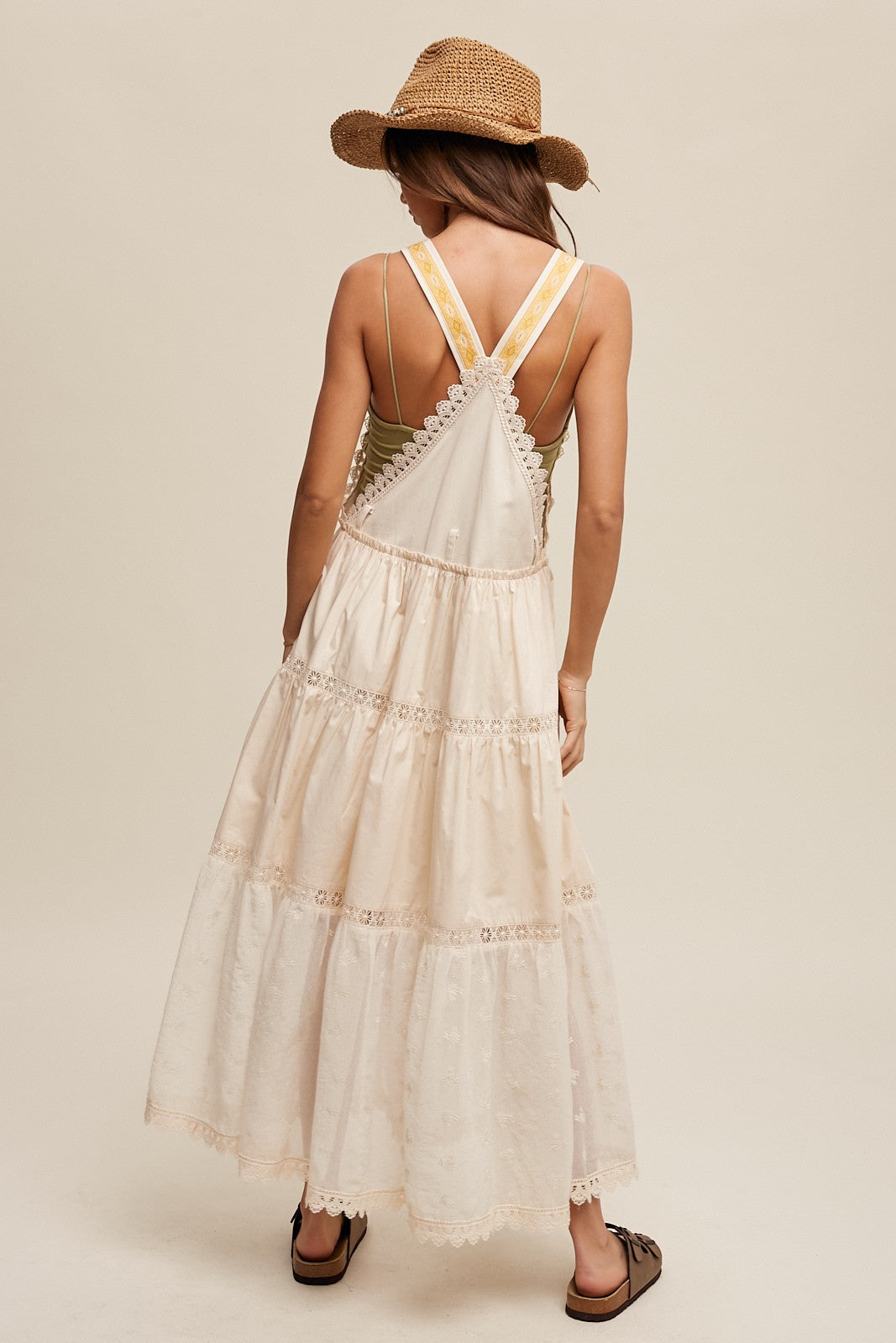 Step into summer romance with our Brooklynn Laced and Tiered Romantic Overall Maxi Dress. It features adjustable straps, a delicate kangaroo pocket, and embroidered crochet lace on the tiered skirt for a whimsical touch.