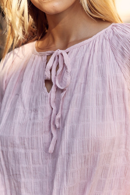 The Maisie Textured Tie Neck Blouse is a soft and versatile piece for your wardrobe. With a textured fabric and a stylish tie neck detail, this blouse exudes elegance and charm. Perfect for pairing with skirts or trousers any days of the week.